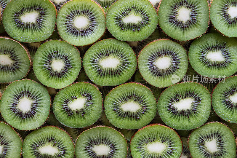 猕猴桃(Actinidia chinensis)切片的全帧图像，中国醋栗显示模糊的棕色皮肤和亮绿色的果肉，黑色的种子环，健康饮食海报壁纸背景设计，高架视图